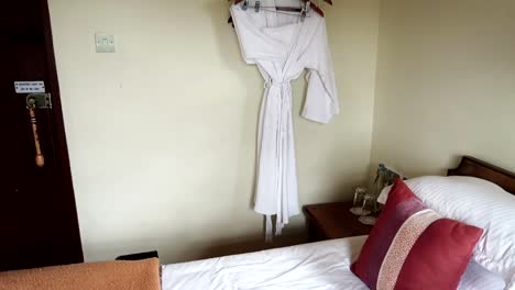 Tilt-up-interior-view-of-hotel-room-with-double-bed,-african-keyring-and-bathrobe,-day