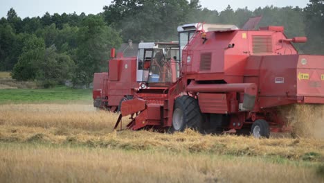 Paar-Rote-Traktor-Erntemaschinen,-Die-In-Der-Erntesaison-Auf-Dem-Bio-Feld-Des-Ackerlandes-Als-Team-Zusammenarbeiten