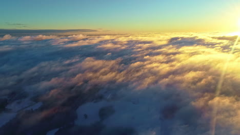 Stunning-Sunrise-above-clouds,-Aerial-pullback-revealing-clouds-pattern-in-Sunlight