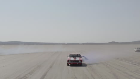 Aerial-shot-of-multiple-muscle-cars-traveling-through-the-desert-holding-flares