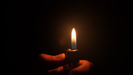 close-up-fire-from-the-lighter-igniting-in-the-hand-in-the-dark-on-a-dark-room