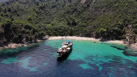 An-old-wooden-ship-anchored-in-a-secluded-spot,-Robinson-beach,-Sithonia,-Greece