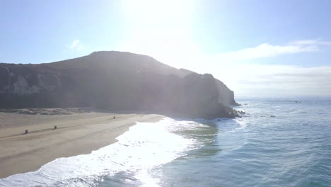 Dolly-backward-shot-revealing-the-beach-with-large-waves-crashing