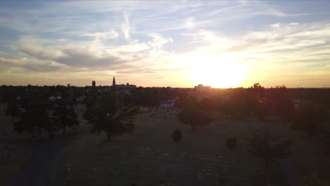 Ascending-aerial-shot-of-the-sun-setting-over-the-graveyard