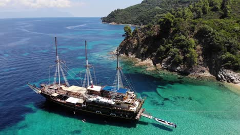 An-old-wooden-ship-anchored-in-a-secluded-spot,-Robinson-beach,-Sithonia,-Greece