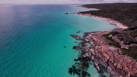 Aerial-fly-along-the-coast-of-the-crystal-clear-turquoise-waters-and-orange-rocks-of-castle-rock,-Western-Australia