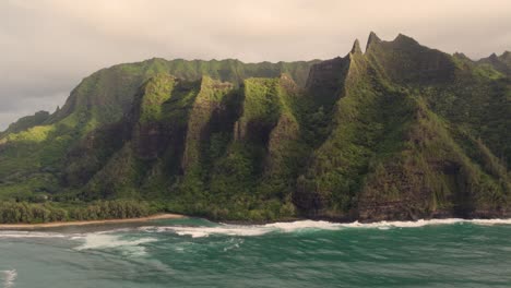 Beautiful-nature-drone-view-of-green-jungle-mountain-peaks-revealing-tropical-beach-on-Na-Pali-park-4K