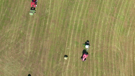 Aerial-top-down-of-Tractors-Collecting-Hay-Bale-In-The-Field-in-Summer
