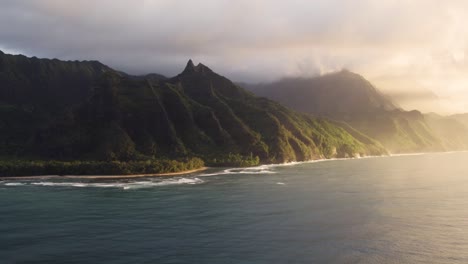 Epic-aerial-above-Hawaii-coast-landscape-of-Haena-park,-panoramic-views-on-NaPali-coast-park-with-green-tropical-jungle-mountain-peaks-covered-by-rain-clouds