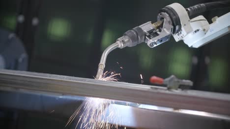 Footage-of-sparks-falling-off-a-steel-frame-while-a-robotic-welder-is-working-on-it