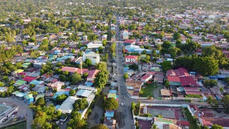 Aerial-drone-lowering-to-reveal-rugged-mountainous-and-hilly-landscape-surrounding-capital-Dili,-Timor-Leste-in-Southeast-Asia,-with-residential-houses,-businesses-and-traffic