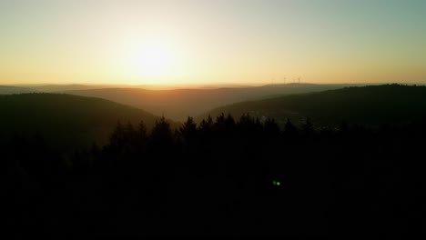 Sunrise-from-drone-over-a-forest-passing-a-tower