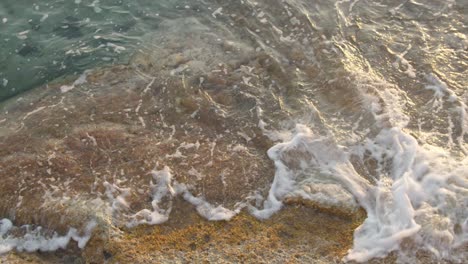 Slow-Motion-Mediterranean-Sea-Waves-Flowing-Over-Rocks-With-Seaweed,-Close-Up