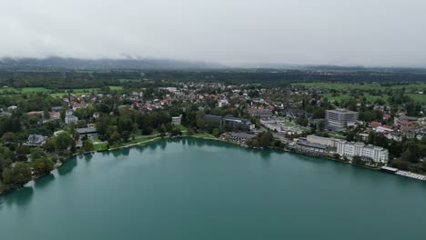 Bled-Town-Y-Waterfront-Eslovenia-Drone-Vista-Aérea-Nubes-Bajas-En-Segundo-Plano.