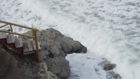 Slow-Motion-Strong,-Wild-Sea-Waves-Crashing-Into-a-Wooden-Staircase-and-Rocks-in-Cyprus