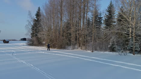 Drone-tracking-shot-of-Person-cross-country-skiing-on-white-winter-landscape-in-forest