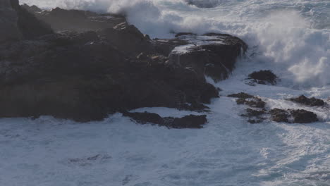 Stationary-shot-of-waves-crashing-against-the-massive-boulder-on-a-Big-Sur-California-Beach