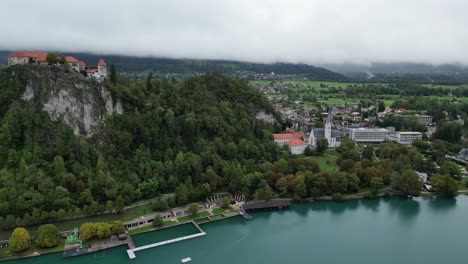 Burg-Bled-Slowenien-Drohne-Luftaufnahme-Schwenken-Niedrige-Wolke-Auf-Fernen-Bergen