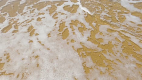 Sea-wave-with-foam-crashing-into-beach-sand