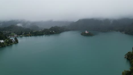 Lake-Bled-Slovenia-drone-aerial-view-misty-mountains-in-background