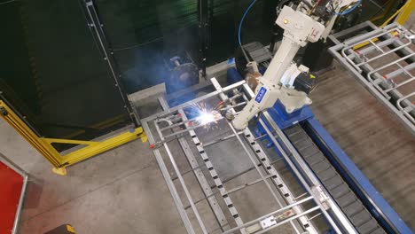 Aerial-footage-rotating-around-a-robotic-welder-putting-welds-on-a-steel-frame