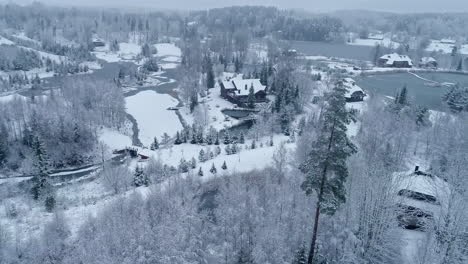Drone-circling-above-an-empty-rural-town-and-beautiful-landscape-entirely-covered-with-snow-with-snowy-forest-in-the-background
