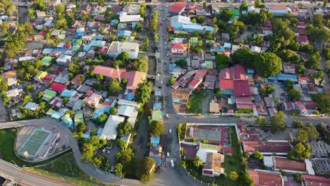 Birdseye-view-of-inner-city-main-road-with-people-and-vehicles-commuting-home,-colorful-tinned-roof-buildings-and-tree-greenery-in-Dili,-Timor-Leste,-South-East-Asia,-static-aerial-drone