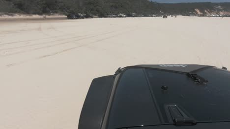 Schwarzer-Jeep-Fährt-Am-Weißen-Sandstrand,-Der-Mit-Anderen-4x4-Autos-überfüllt-Ist