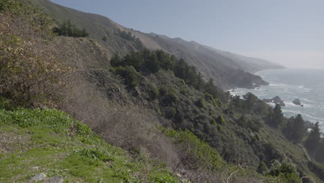panning-shot-of-mountain-side-to-Pacific-ocean-at-Big-Sur-California-on-a-sunny-summer-day