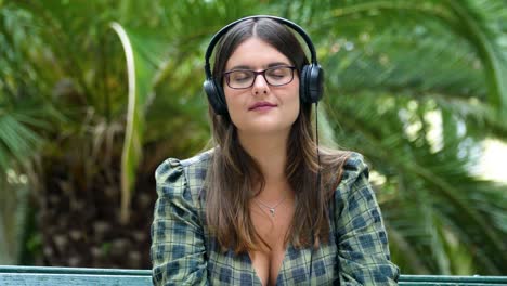 Girl-listening-to-music-on-headphones-with-closed-eyes-in-the-park