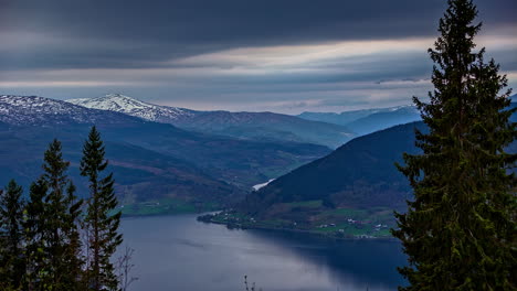 Zeitrafferaufnahme-Aus-Der-Luft-Eines-Idyllischen-Fjords-Und-Dunkler-Wolken,-Die-Schneebedeckte-Berge-In-Norwegen-Bedecken