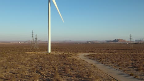 Aerial-rising-view-Alternative-energy-wind-turbine-rotating-in-Mojave-desert-dry-landscape