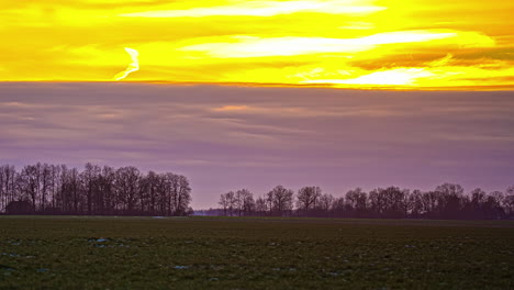 Static-shot-of-sunset-behind-dark-clouds-in-the-bright-yellow-sky-in-timelapse-during-evening-time