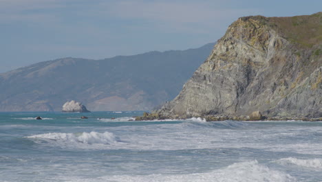 Stationary-shot-of-waves-rolling-into-the-side-of-high-cliff-located-in-Big-Sur-California