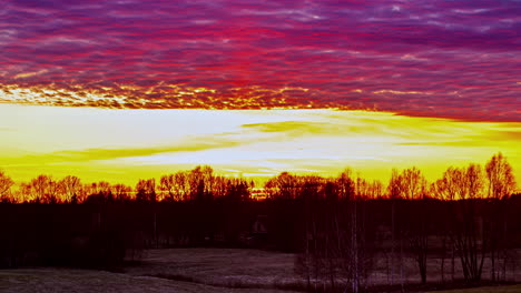 Static-shot-of-purple-clouds-passing-by-over-beautiful-yellow-sky-during-sunset-over-the-horizon-in-timelapse