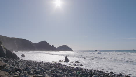 Low-stationary-shot-of-waves-crashing-along-the-rocky-shores-of-Big-Sur-California-Beach-on-a-sunny-summer-day