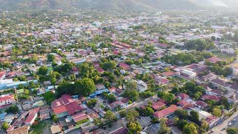 Aerial-drone-rising-over-capital-Dili,-Timor-Leste-in-Southeast-Asia,-with-beautiful-views-of-densely-packed-houses,-businesses,-buildings,-and-green-tree-from-above