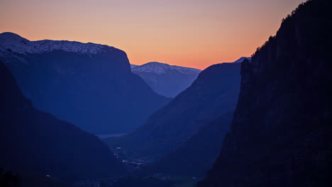 Time-lapse-panorama-wide-shot-of-golden-sunset-behind-snowy-mountain-range-in-Norway