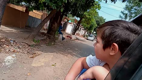 Cute-Little-Boy-Sticking-Head-Out-Of-Car-Window-While-Enjoying-Nice-Car-Ride,-Paraguay