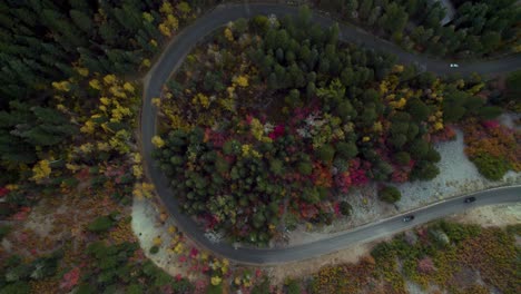 Cars-drive-on-a-winding-mountain-road-among-autumn-colored-trees
