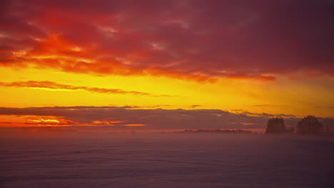 Time-lapse-shot-of-yellow-sunset-over-foggy-landscape-with-flying-clouds-in-nature