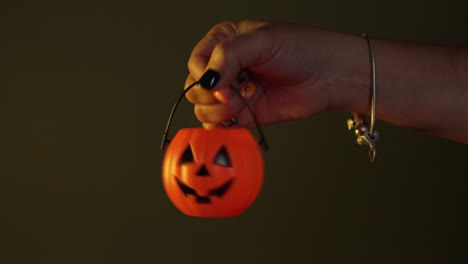 Weibliche-Hand-Baumelnder-Mini-Halloween-Kürbiskorb