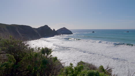 mountainside-view-of-waves-rolling-in-along-the-shores-of-Big-Sur-California-beach,-Pacific-Ocean