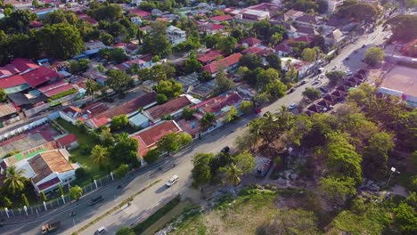 Aerial-drone-revealing-panorama-view-of-capital-Dili,-Timor-Leste-landscape-of-red-roofed-houses,-businesses-and-green-trees-with-rugged-hills-in-distance,-Southeast-Asia