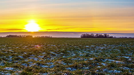 Zeitraffer-Sonnenuntergang-Am-Abend-über-Schmelzendem-Schnee-Auf-Grasfeldern