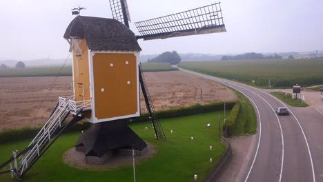 DMC-DeLorean-driving-on-road-near-windmill,-seen-from-above