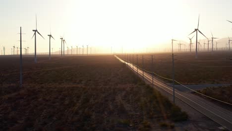 Windturbinenpark-Mit-Goldgelbem-Sonnenuntergangshimmel-Mit-Blick-Auf-Die-Leere-Straße,-Die-In-Der-Mojave-Wüste-In-Den-Horizont-Abgeht