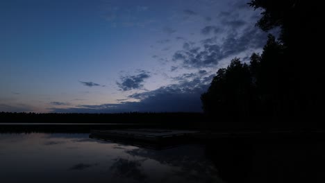 Tranquil-lake-dock-time-lapse-as-forest-blue-evening-turns-to-night