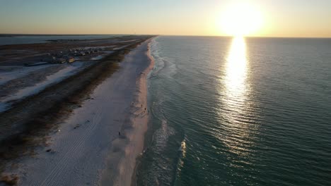 Drone-flying-thou-dunes-with-sea-oats-at-sunrise-to-the-white-sand-beach-clear-emerald-waters-to-view-of-the-fishing-pier-on-Navarre-beach