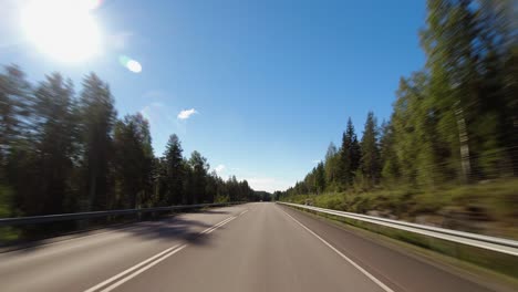 Blue-sky-driving-POV-on-highway-through-northern-evergreen-forest